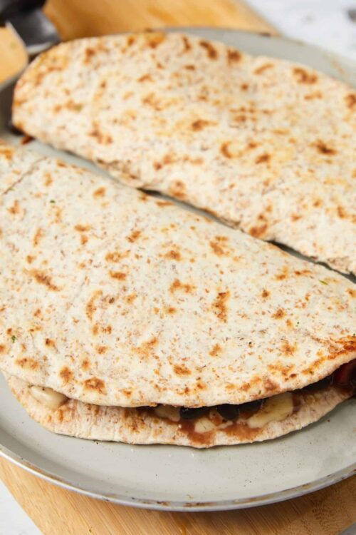 Crispy quesadilla with cheese and black beans on a white plate.