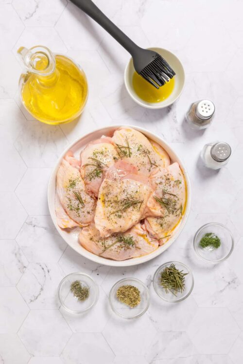 Juicy chicken thighs marinating with herbs and olive oil before cooking.