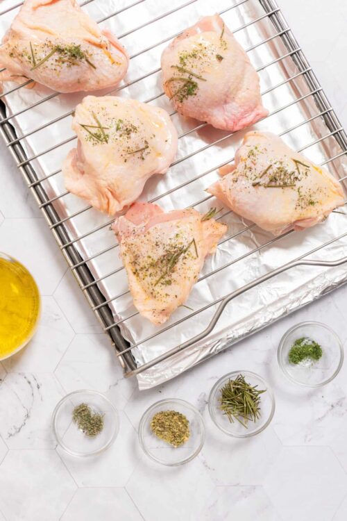 Juicy baked chicken thighs seasoned with herbs ready for roasting. Perfect for delicious homemade chicken recipes.