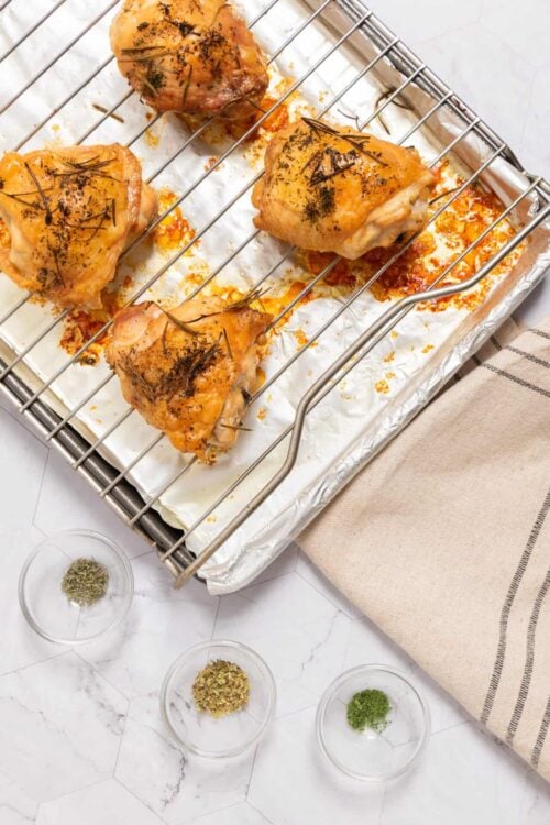 Juicy roasted chicken thighs with herbs on a baking sheet, ready for dinner.