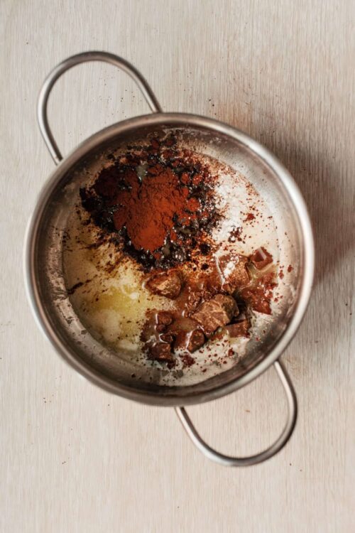 Spice and chocolate mixture in a stainless steel scoop for baking or dessert recipes.
