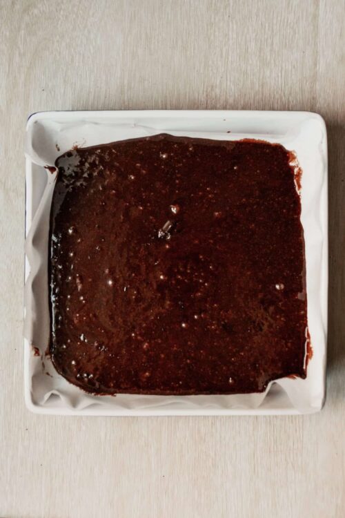 Rich homemade brownie batter in a white baking dish for baking and dessert recipes.