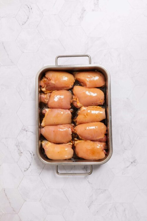 Raw boneless skinless chicken thighs in a baking dish ready for cooking.