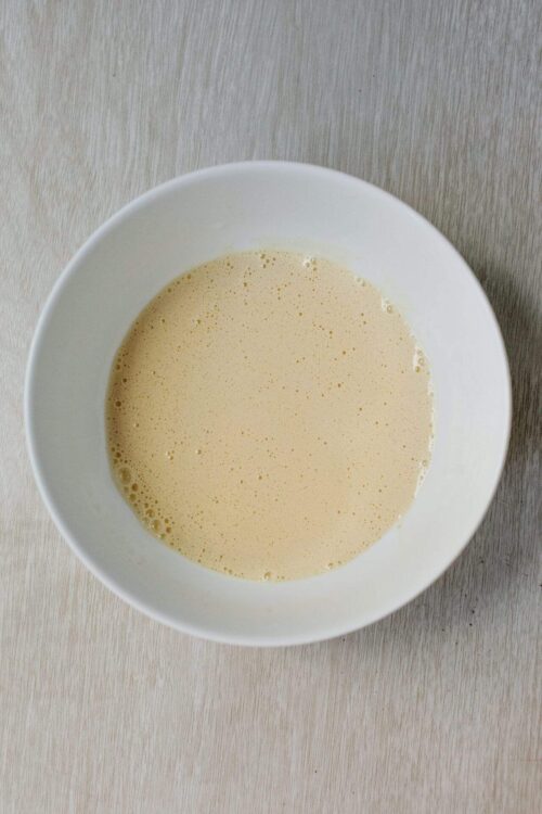Creamy bubble tea in a white bowl on light wooden surface.