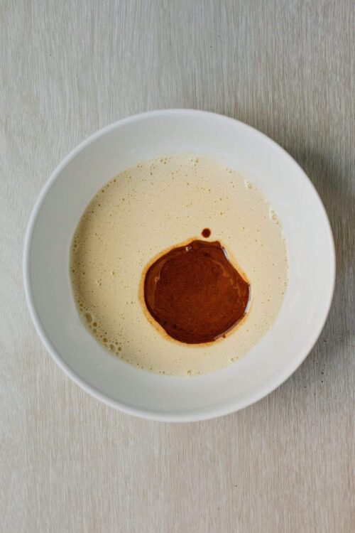 Creamy mixture with a dollop of cinnamon-spiced apple butter in a white bowl on a light wooden surface.
