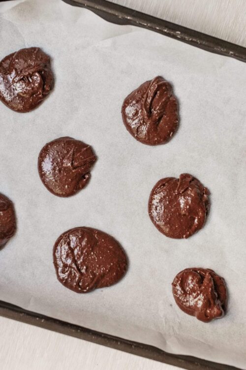 Fudgy chocolate cookie dough balls on parchment paper before baking. Perfect for homemade chocolate treats and dessert recipes.