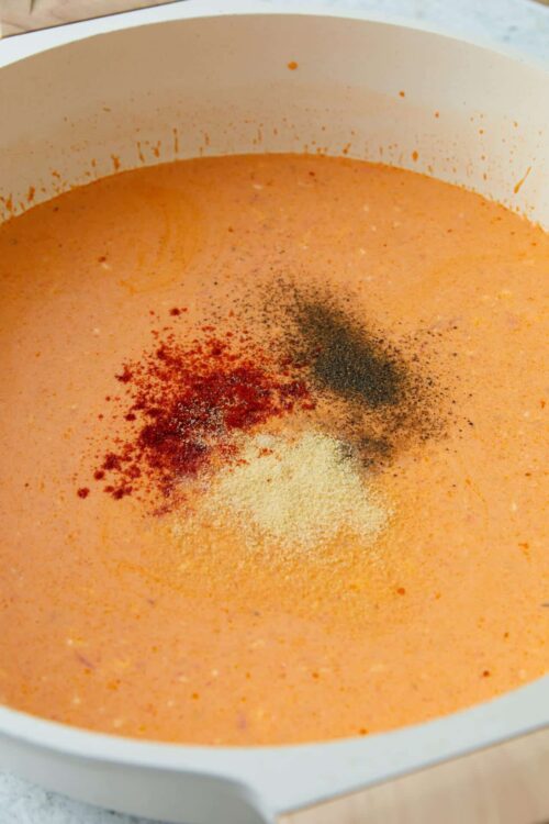 Creamy tomato soup with spices in a white pot.