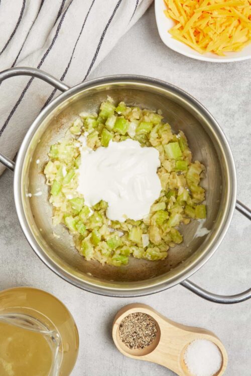 Sautéed celery with cream cheese in a stainless steel skillet.