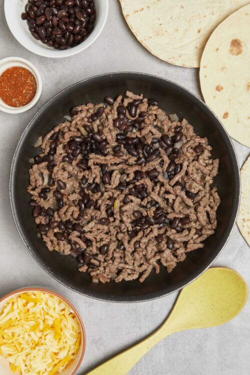Ground beef and black beans in a skillet for taco filling.