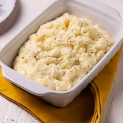 Creamy mashed potatoes with black pepper in a rectangular white dish.