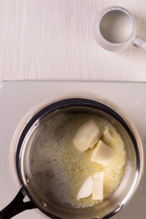 Cream being melted in a saucepan on stovetop for baking recipes.