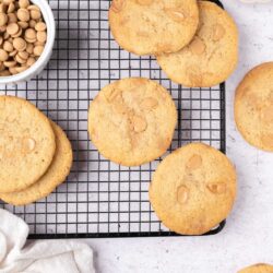 Buttery white chocolate chip cookies on a cooling rack with white chocolate chips.