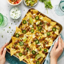 Crunchy loaded nachos with jalapenos, cheese, and seasoned beef in a serving tray. Perfect for casual gatherings and game day snacks.