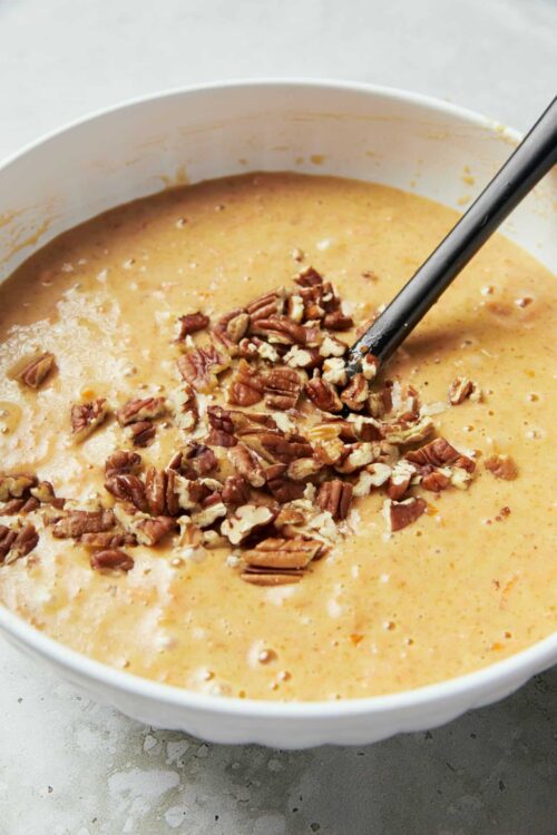 Creamy pumpkin soup with chopped walnuts in a white bowl for fall comfort food.