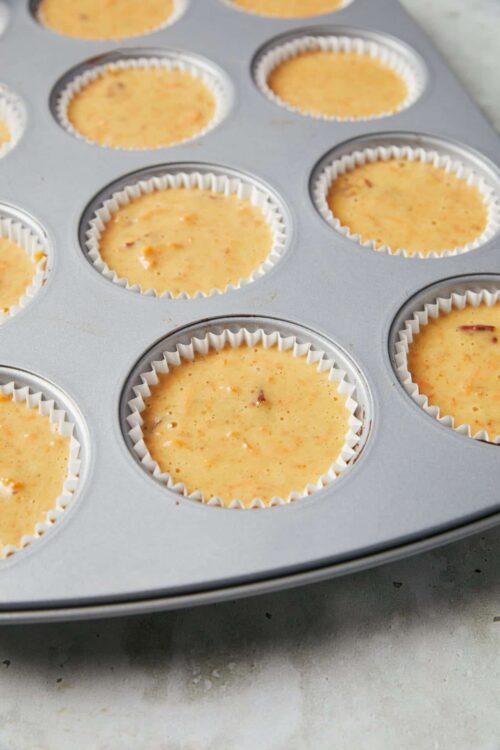 Creamy baked cheesecake batter in muffin tins ready to bake, featuring a classic dessert recipe.