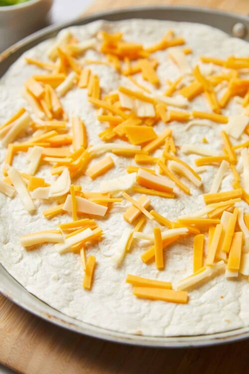 Shredded cheddar and Monterey Jack cheese topping on a pizza dough.