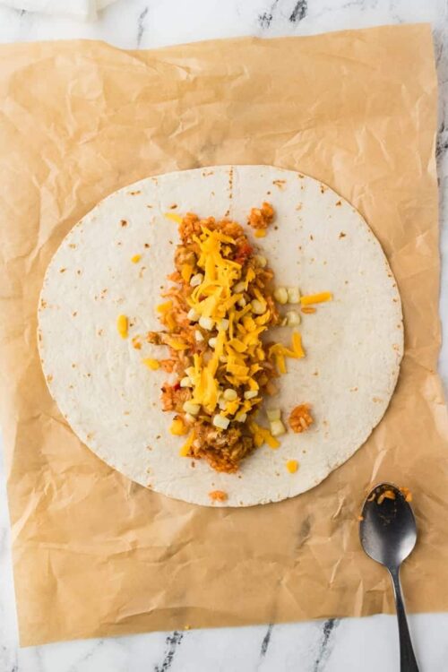 Cheese and seasoned meat filling on a flour tortilla for tacos or burritos.