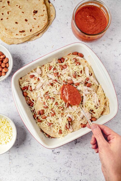 Baked chicken enchiladas with cheese and beans before baking, prepared for oven.