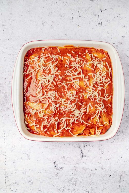 Cheesy baked lasagna in a white ceramic dish.