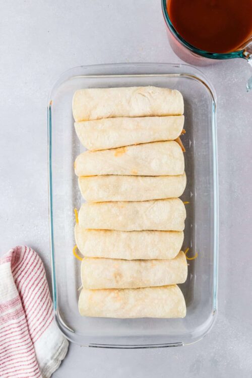 Golden baked cinnamon rolls in a glass pan ready for baking.