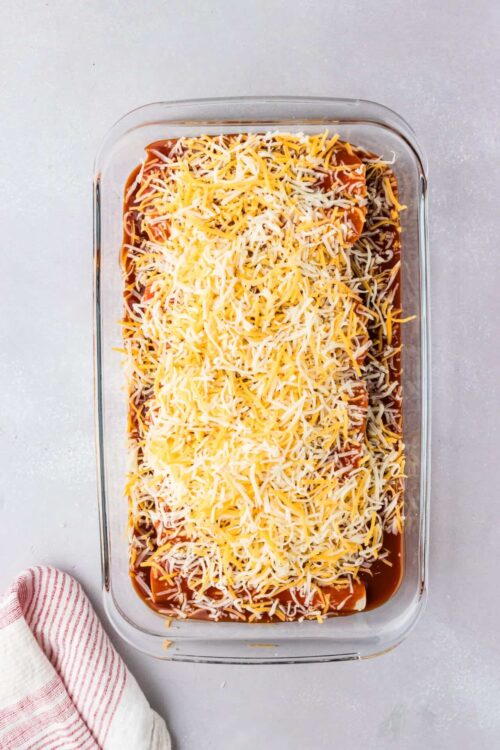 Shredded cheese topping a layered casserole dish ready for baking.