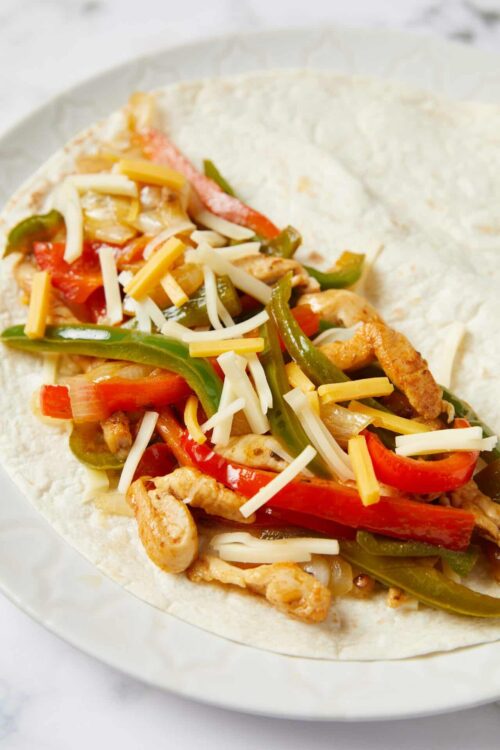 Colorful chicken and vegetable fajita on a soft flour tortilla.