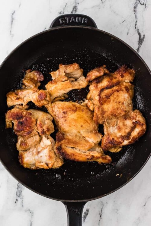 Crispy sautéed chicken thighs in a cast iron skillet.