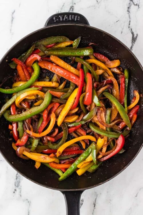 Colorful sautéed bell peppers in a black cast iron skillet for healthy cooking.