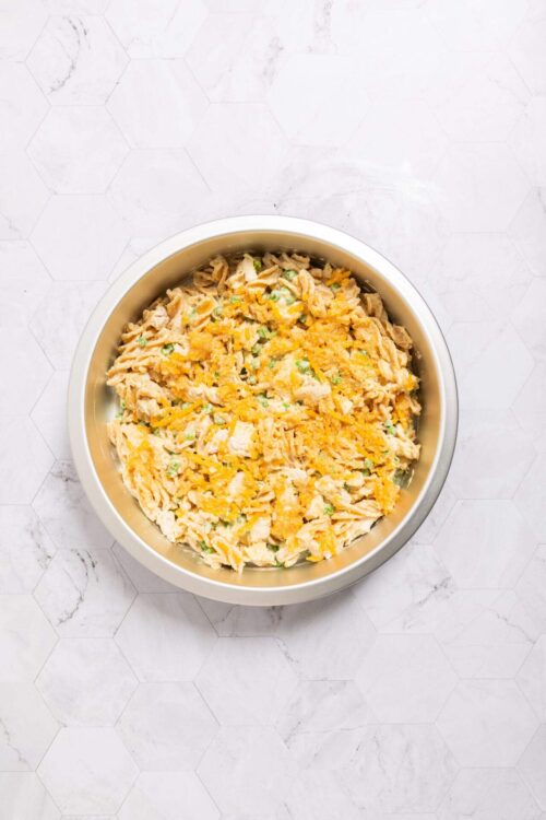 Creamy chicken salad with shredded chicken, hard-boiled eggs, and fresh green herbs in a white bowl.