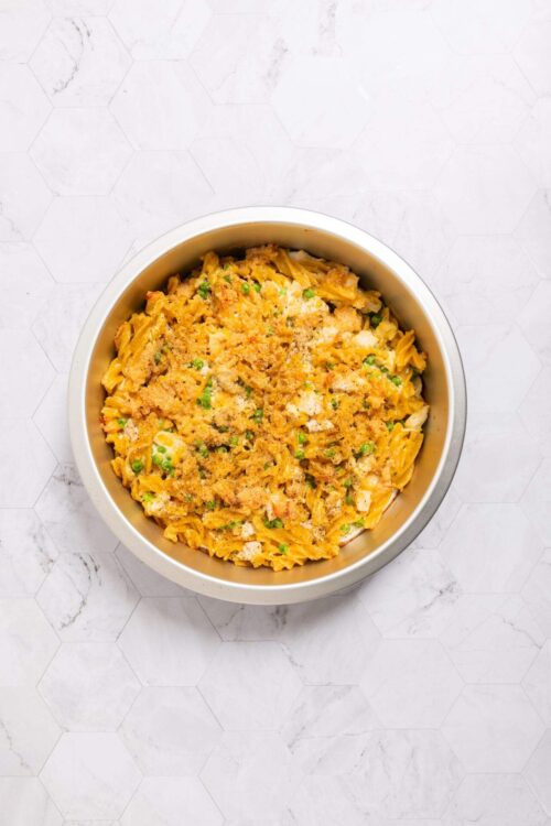 Creamy macaroni and cheese with bread crumbs and green onions in a white bowl.