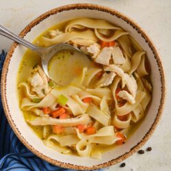 Creamy chicken noodle soup with vegetables in a rustic bowl, served hot and comforting.
