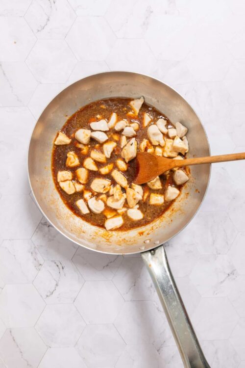 Cooked chicken in spicy sauce in a skillet, ready for shredding or serving.