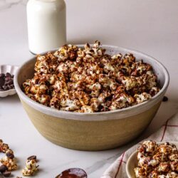 Buttery caramel popcorn drizzled with chocolate in a rustic bowl, perfect for snacking or movie night.