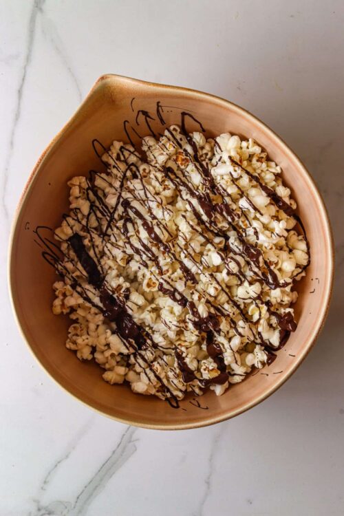 Buttered popcorn with chocolate drizzle in a bowl.