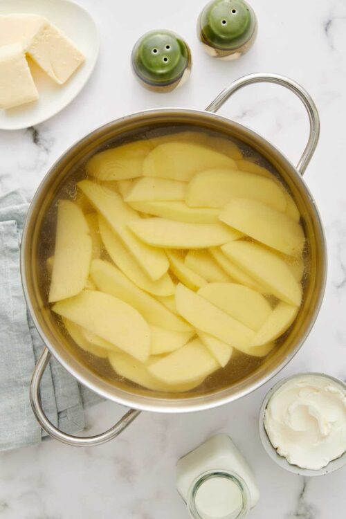 Sliced potatoes boiling in a pot for a creamy mashed potato recipe.