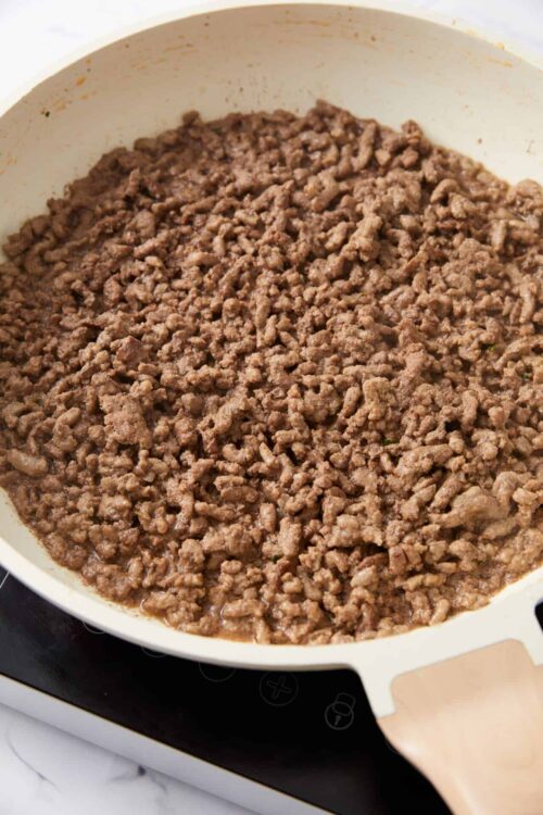 Ground beef cooking in a white skillet on an induction cooktop.