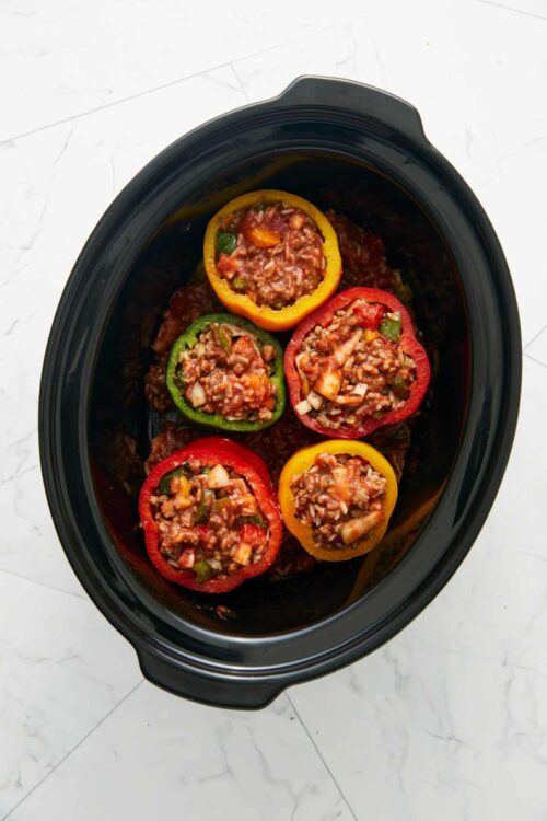 Colorful stuffed bell peppers in a slow cooker.