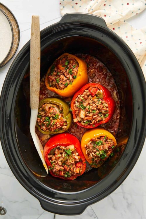 Stuffed bell peppers in a slow cooker, filled with seasoned ground beef, rice, and vegetables. Perfect for easy, flavorful dinner recipes.