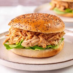 Shredded barbecue chicken sandwich on a sesame seed bun with lettuce at Baked Bree.