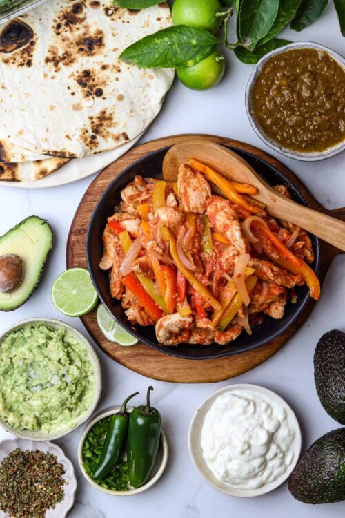 Savory chicken fajitas with colorful peppers, served with fresh salsa and avocado slices.