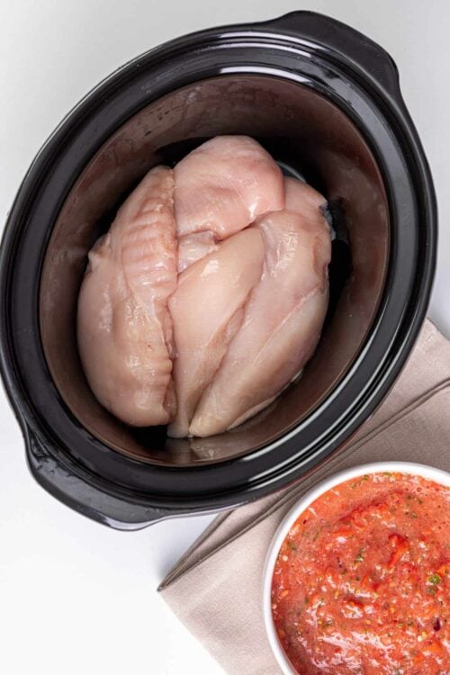 Raw chicken breasts in a slow cooker, ready for cooking or meal prep.