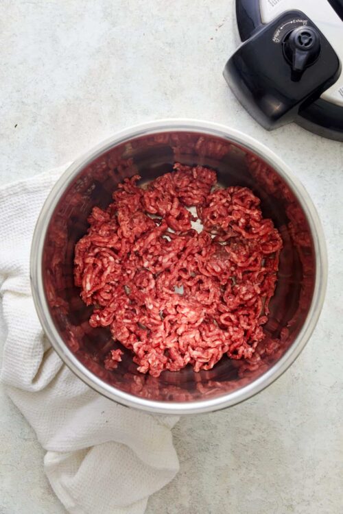 Ground beef in a stainless steel food processor bowl for cooking recipes.