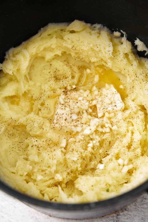 Creamy mashed potatoes with butter, garlic, and black pepper in a cooking pot.