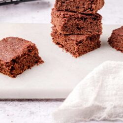 Fudgy homemade chocolate brownies stacked on a white marble surface, fresh and gooey.