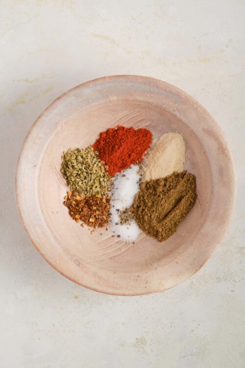 Ground spices and herbs for baking and cooking in a pink ceramic bowl, ready to add flavor to recipes.