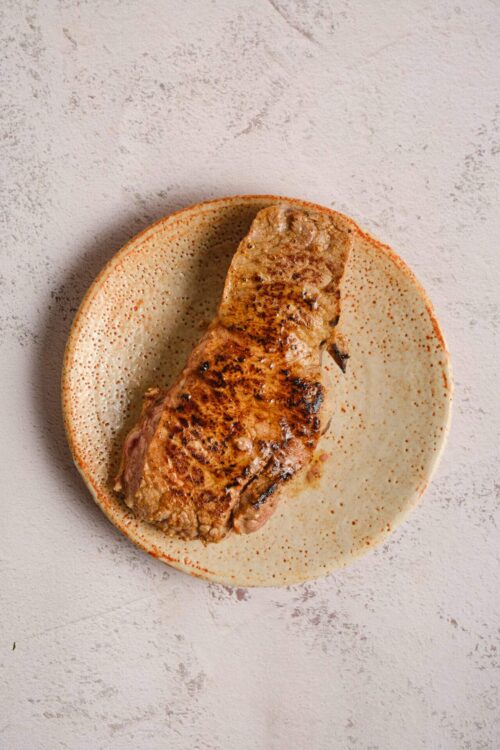 Juicy grilled steak on a textured plate.