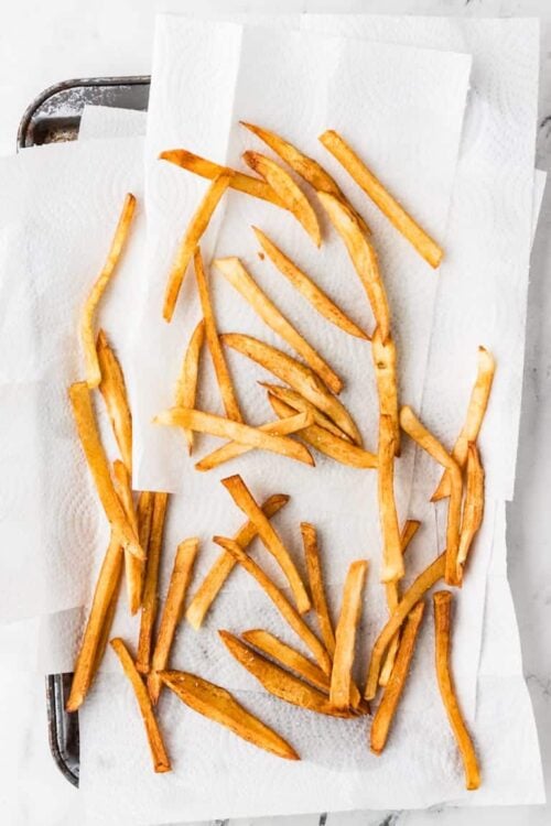 Golden crispy baked French fries on parchment paper.