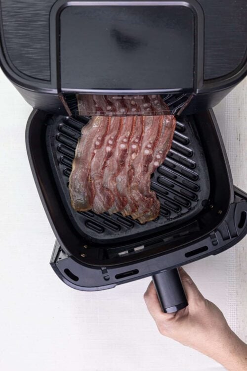 Crispy bacon strips cooking in an air fryer for perfect breakfast bacon.