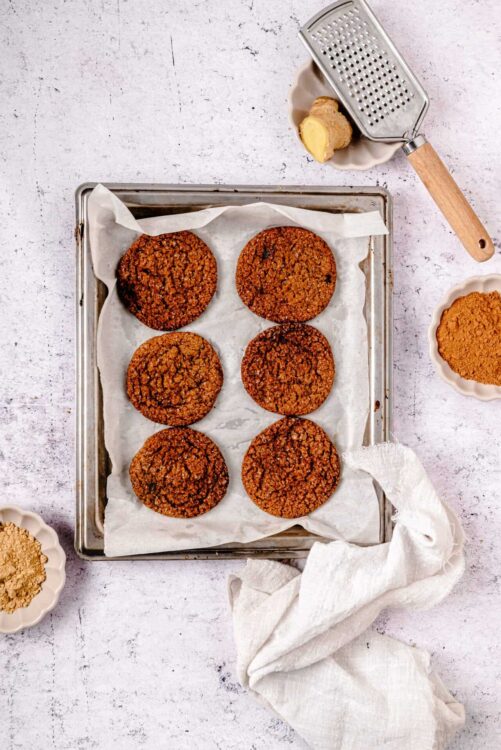 Freshly baked oatmeal raisin cookies on parchment paper in a baking sheet.