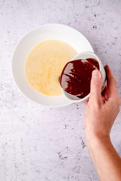 Creamy custard base with melted chocolate being poured, baking dessert ingredients.